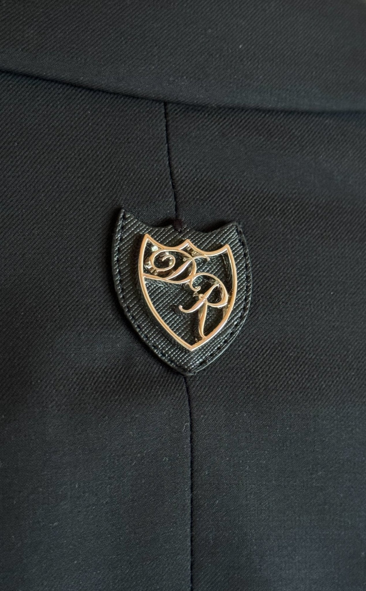 Rückansicht des schwarzen Signature Anzugs - doppelte Rückenschlitze und dezentes Metalllogo zeugen von meisterhafter Detailarbeit.