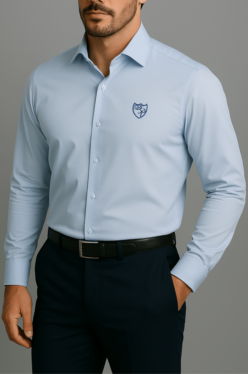 Hellblaues Signature Hemd aus feinster italienischer Baumwolle mit edlem dunkelblauen Wappenlogo - lässige Frontansicht mit Hand-in-der-Tasche-Geste, Ausdruck entspannter Eleganz.