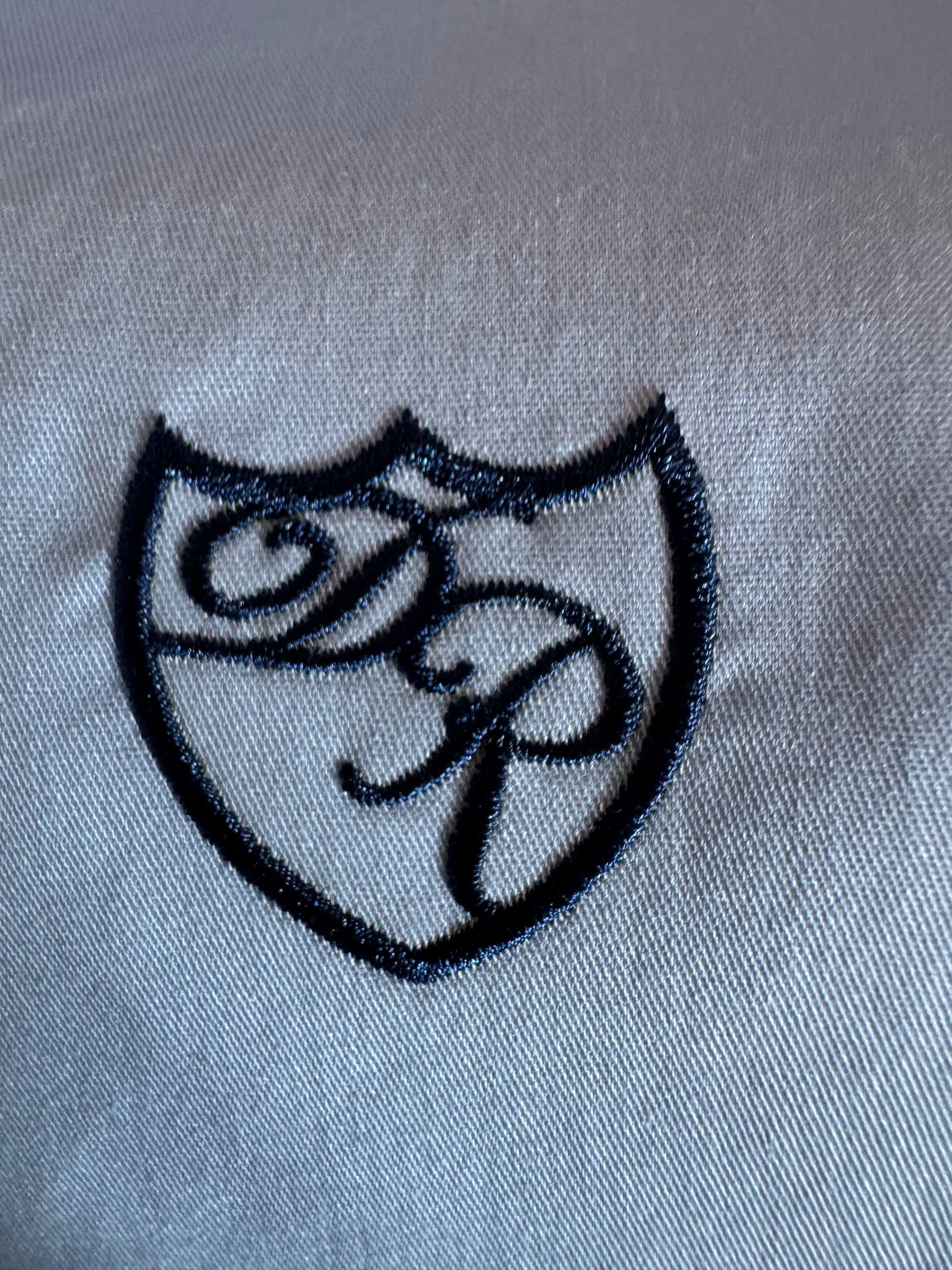 Handgefertigte Wappenstickerei in leuchtendem Königsblau - Symbol für höchste Exklusivität.