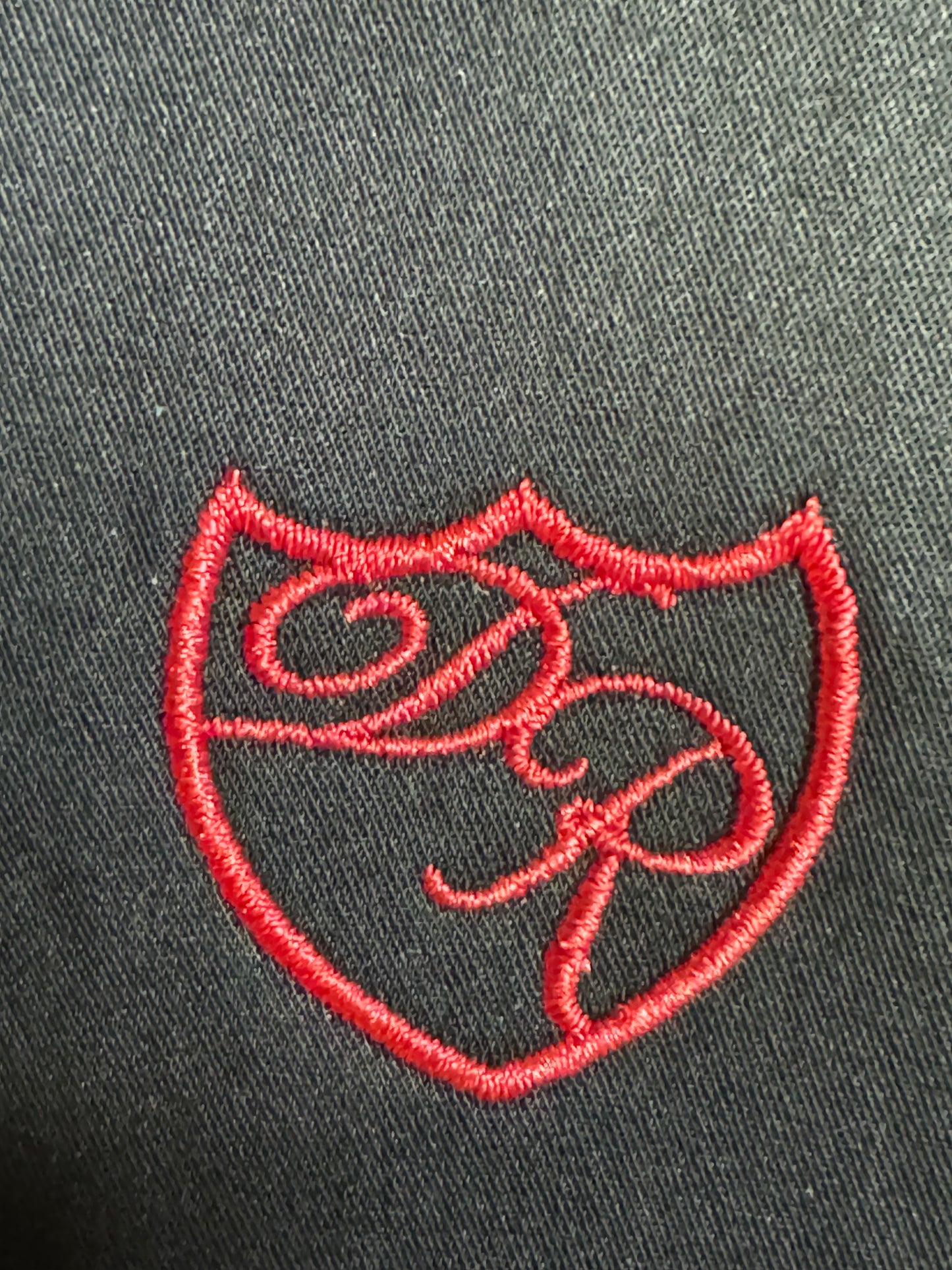 Präzise handgesticktes Wappenlogo in leuchtendem Rot - Symbol für kraftvolle Eleganz und höchste Handwerkskunst. 