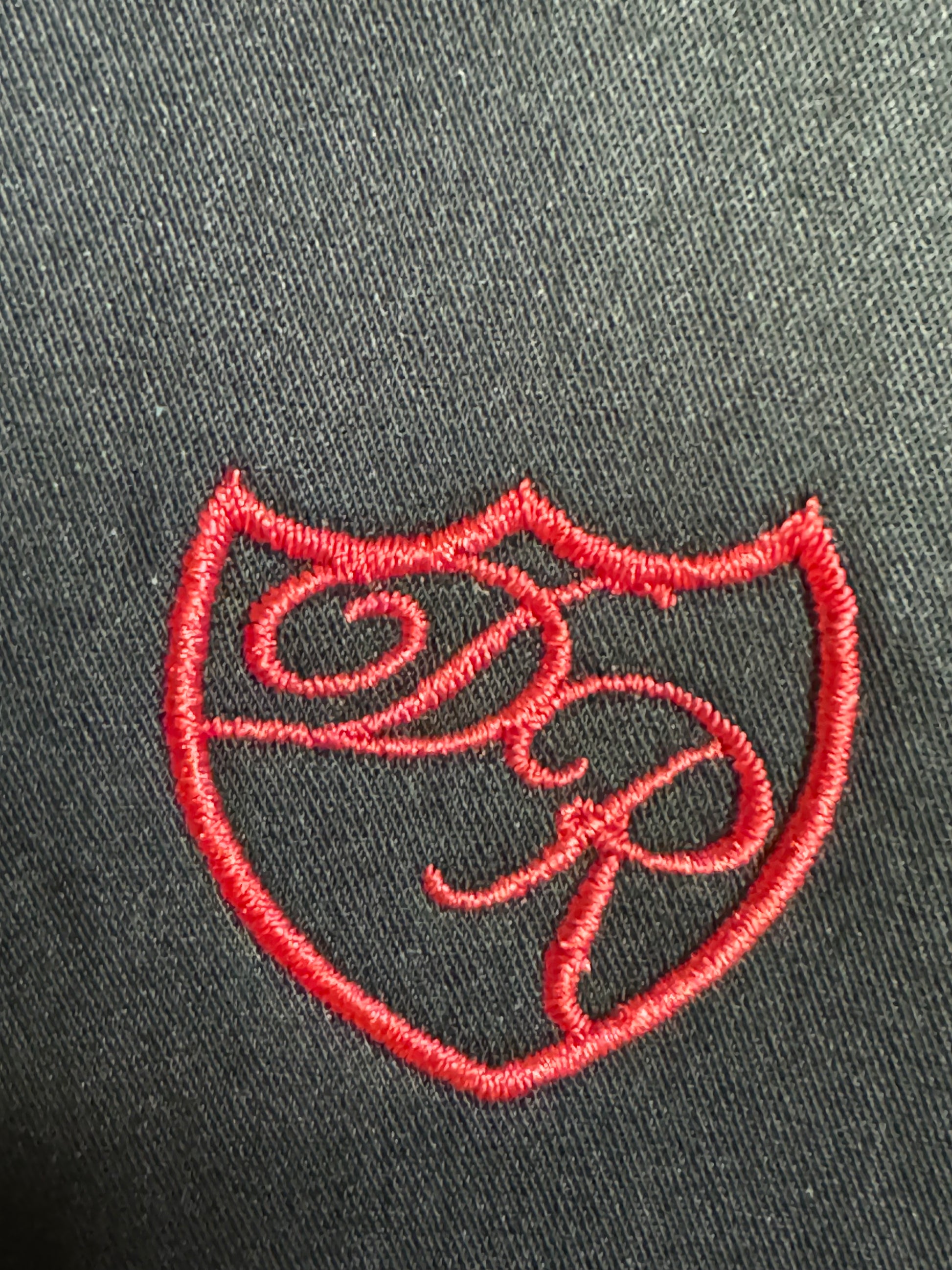 Präzise handgesticktes Wappenlogo in leuchtendem Rot - Symbol für kraftvolle Eleganz und höchste Handwerkskunst. 