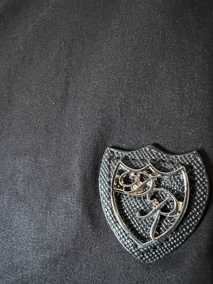 Exklusives Metallwappen auf strukturiertem schwarzem Saffianleder - Ausdruck ikonischer Designästhetik. 