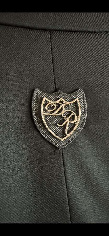 Exklusives Metalllogo Daniel Rügamer - luxuriöse verarbeitet auf der Passe des schwarzen Signature Anzugs.