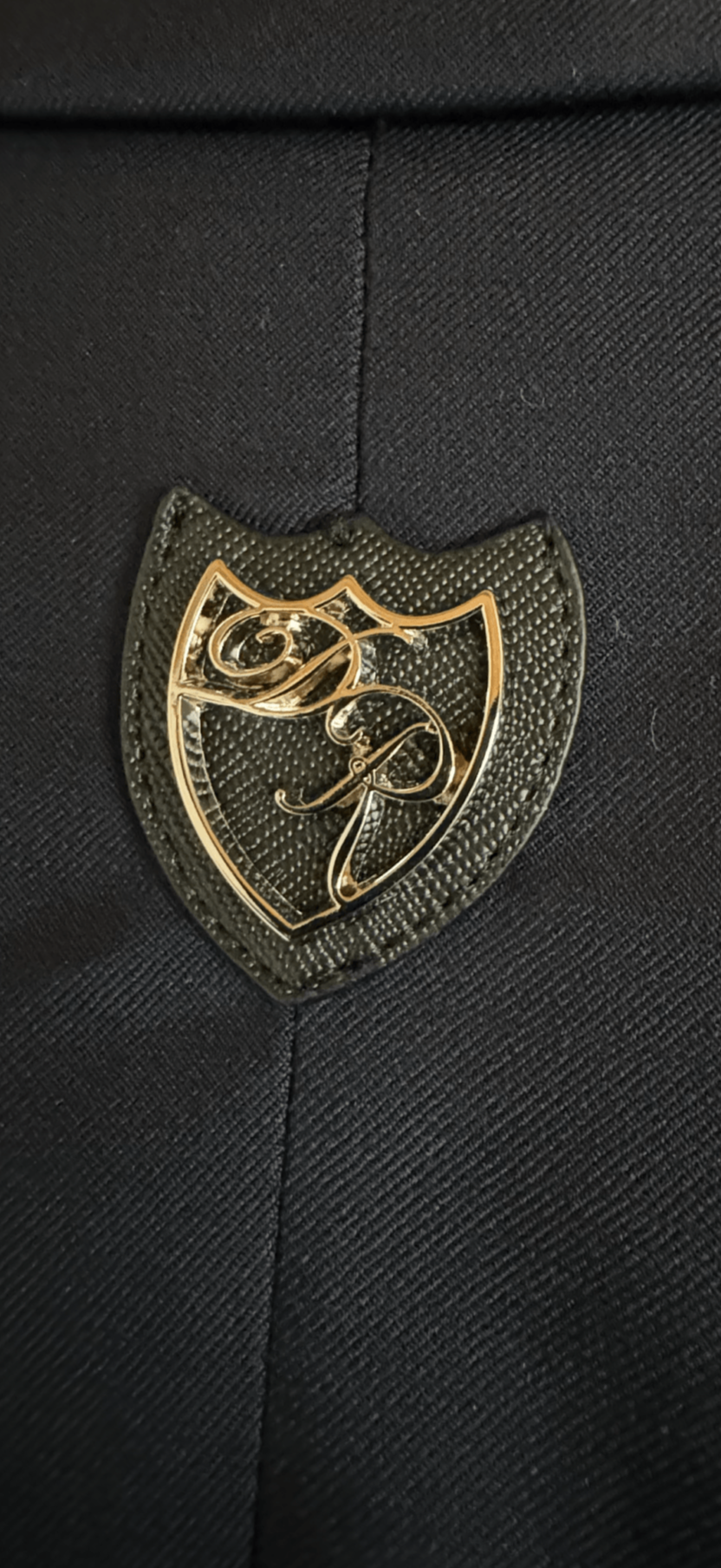 Ikonisches Metalllogo Daniel Rügamer auf der Passe - edles Designelement für den sportlich-eleganten Signature Anzug.